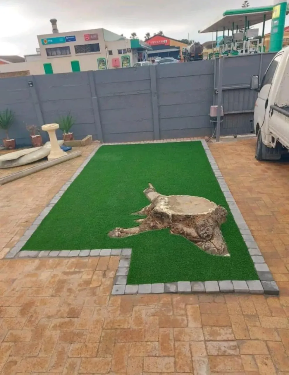 Completed artificial lawn framed by brick paving with a tree-stump feature