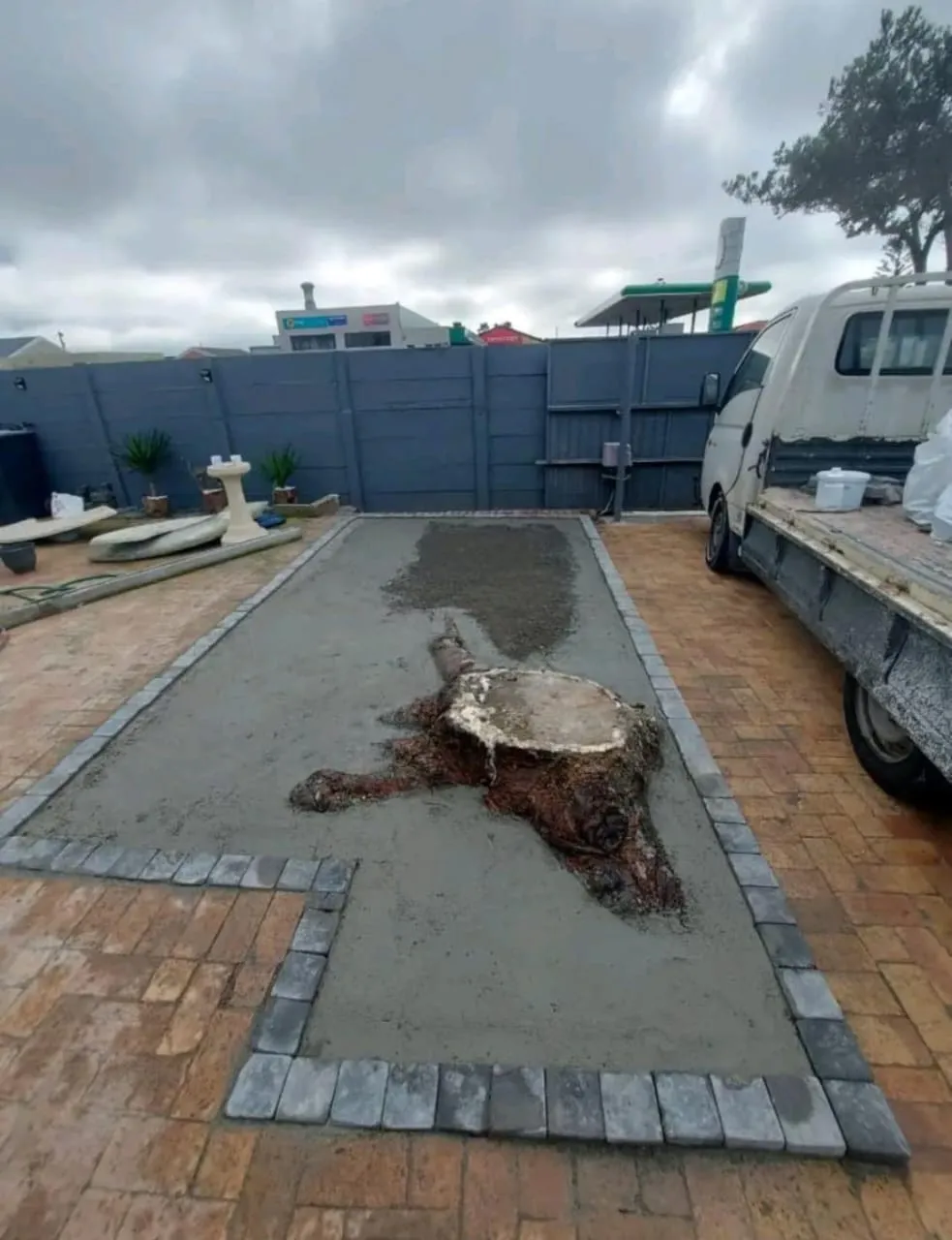 Before: Prepared base before artificial lawn installation, framed by brick paving