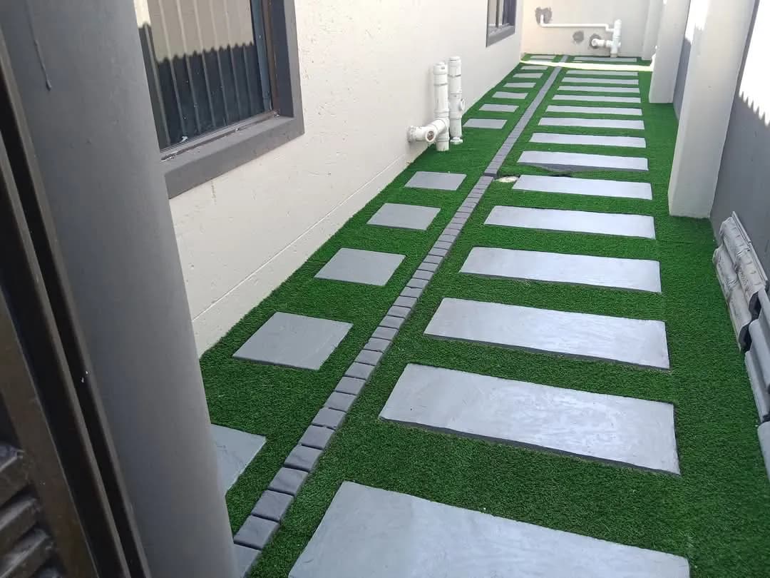 Side passage with large pavers set into artificial grass