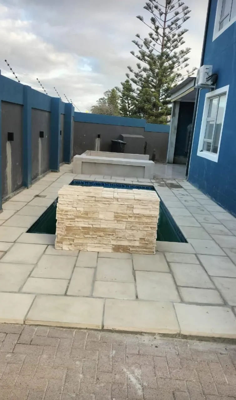 Paved pool area with stone-clad water feature