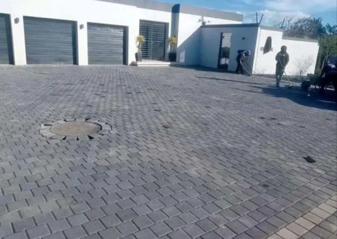 Grey brick driveway in front of a modern double garage