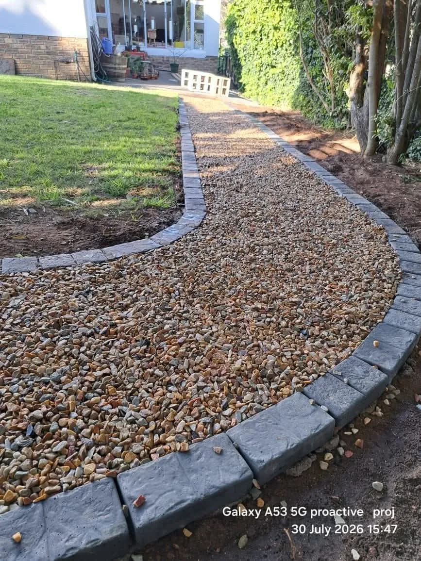 Curved brown pebble path with charcoal brick edging
