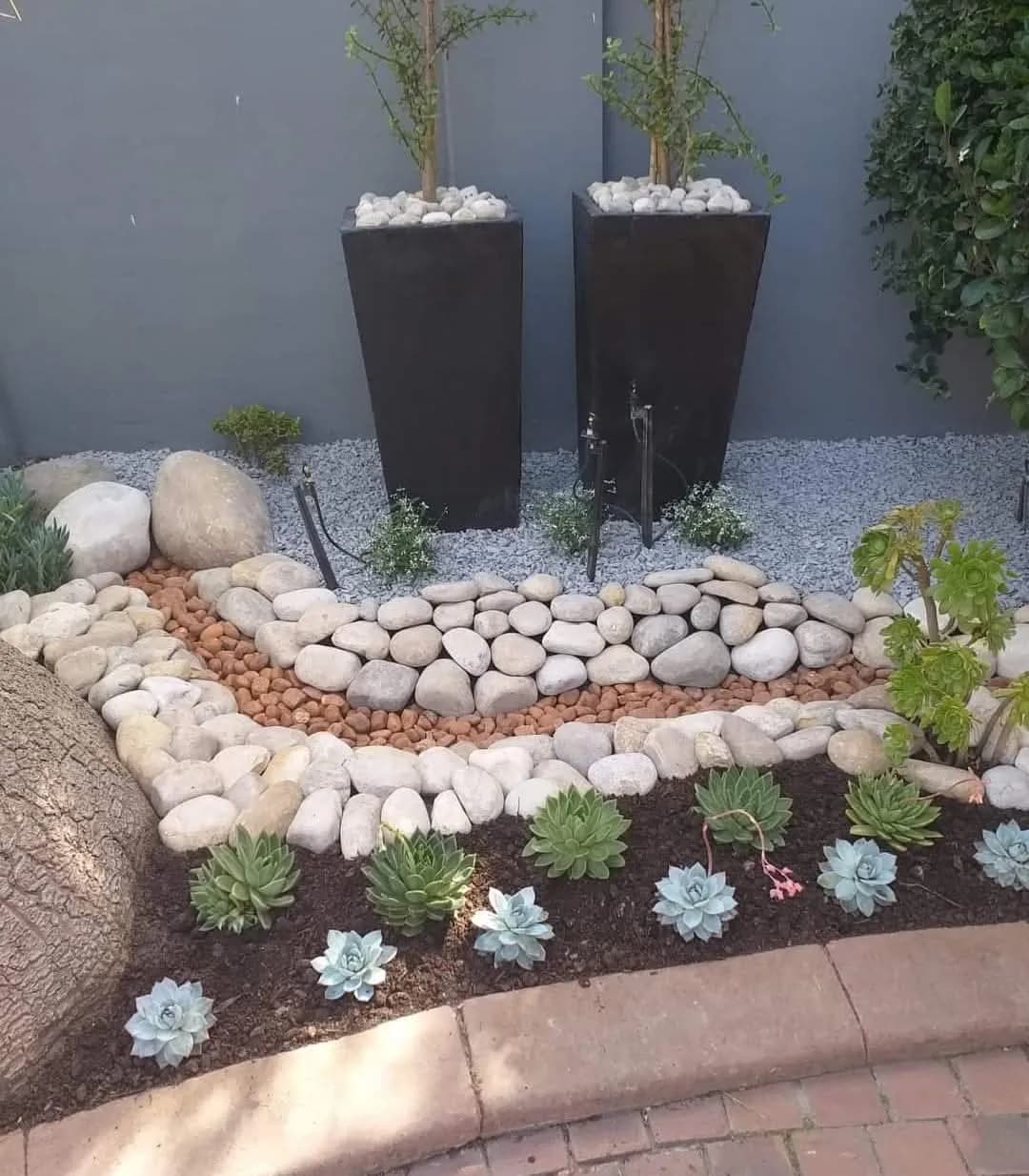 Garden bed edged with large river stones and white pebbles